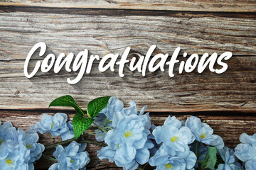 Congratulations text with flowers decoration on wooden background
