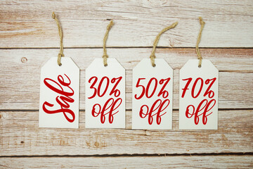 Price tag with "Sale 30%, 50% 70% off" is placed on wooden background