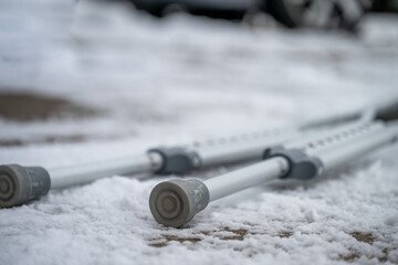 Crutches placed on snowy ground near a parked vehicle in winter after falling