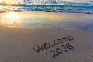 Welcome 2026 written on the sand by the shore