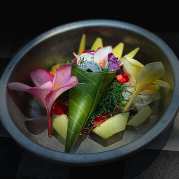 A plate of colorful flowers as a water purification ritual offering in the Balinese temple in Bali, Indonesia