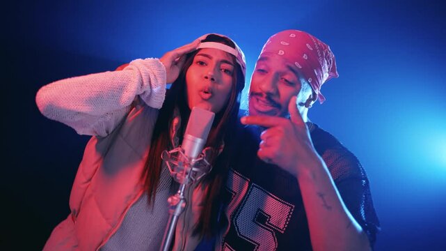 Dynamic singers performing a reggaeton track in a professional recording studio. Passionate male and female artists singing and dancing together