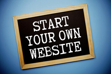 Obraz premium Start Your Own Website text written on chalkboard flat lay on blue background