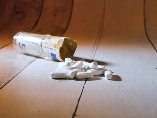 Medicine Cost: Pills and Euro Banknote - White pills spill from a container with a 5 Euro banknote, symbolizing the high cost of medication, healthcare expenses, and drug addiction.