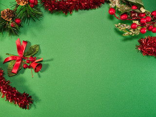 Christmas Green Background Decoration - Vibrant green background adorned with traditional Christmas decorations including pine needles, red berries, tinsel, and a bell, offering copy space.