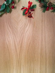 Holiday Wood Background with Copy Space - Festive Christmas decorations, including pinecones, berries, and ribbons, adorn a light wooden background with ample copy space for holiday greetings.