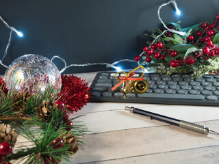 Festive Desk with Christmas Lights - Christmas-themed desk setup with keyboard, glasses, festive ornaments, and string lights on a light wood surface, perfect for holiday work.
