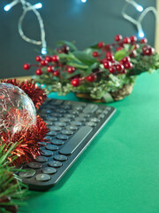 Festive Work: Holiday Tech Decoration - Holiday-decorated desk featuring a sparkling ornament, red tinsel, and keyboard. Perfect for festive work, season's greetings, or online shopping concepts.