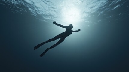 Underwater silhouette of person free diving towards light