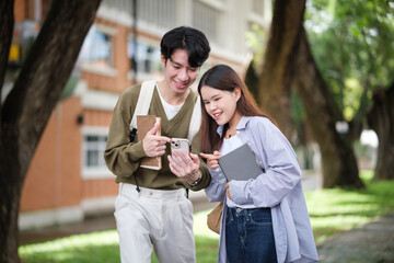 Two university students smiling while looking at a smartphone together on campus.