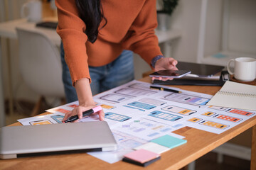UX UI designer reviewing mobile app wireframes at a modern workspace.
