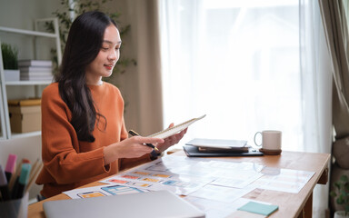 Young female UX UI designer reviewing mobile app wireframes at her workspace.