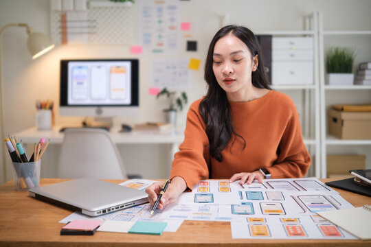 User experience designer planning mobile app structure using wireframes and workflow diagrams. - Powered by Adobe