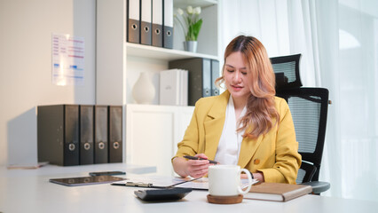 Professional accountant reviewing financial documents at her office desk. Accounting work, financial analysis, and business management concept.