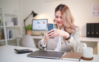 Businesswoman checking her smartphone while working at a modern office desk.