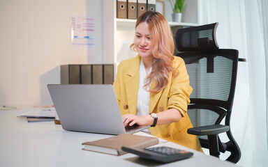 Businesswoman concentrating on her laptop at a desk with office supplies. Career development, office job, and productivity concept.