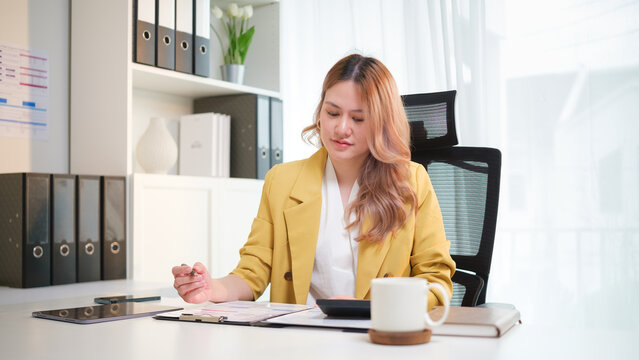 Professional accountant reviewing financial documents at her office desk. Accounting work, financial analysis, and business management concept. - Powered by Adobe