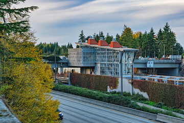 2025-11-19 THE SOUND TRANSIT LIGHT RAIL STATION ON MERCER ISLAND WITH TWO LANES OF 1-90 AND A CLOUDY SKY
