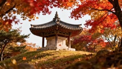 Traditional East Asian stone monument structure nestled on a small grassy mound framed by vibrant red and golden Japanese maple foliage.