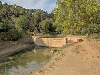 Fototapeta premium Pantano De Vallvidrera water reservoir, almost dried out in summer, in Sierra de Colserolla mountains. Barcelona, catalonia, spain 
