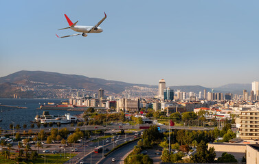White passenger airplane flying over modern city of Izmir - Alsancak, Izmir