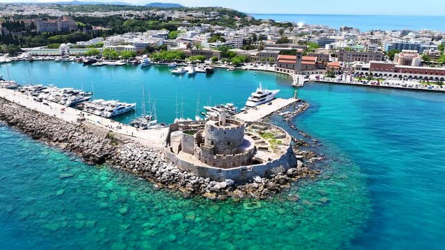 Aerial drone cinematic video of famous Saint Nicholas Fortress built in entrance of Mandraki harbor next to where Colossus of Rhodes was initially built, main town of Rhodes island, Dodecanese, Greece
