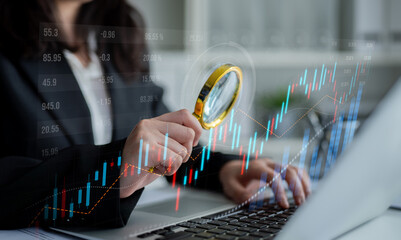 A business professional examines intricate financial data using a magnifying glass over a laptop, reflecting an analytical approach towards market trends in a modern office. Scalp