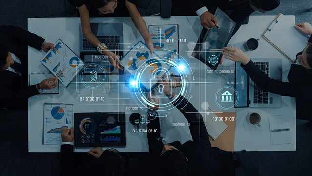 A diverse business team collaborates over data analytics, utilizing modern technology for secure information exchange in a contemporary office setting. Trope - Powered by Adobe