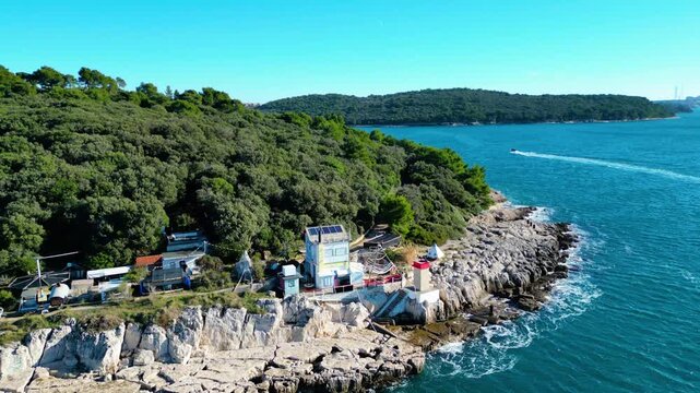 Aerial view lighthouse Rt. Prostina of the rugged Istrian coastline, where emerald waters meet a dense forest and secluded structures. A serene Mediterranean escape.