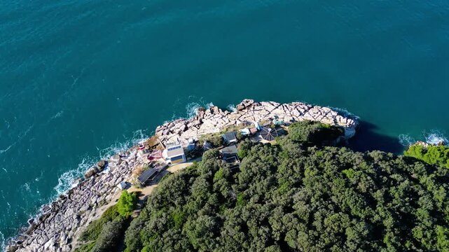 Aerial view lighthouse Rt. Prostina of the rugged Istrian coastline, where emerald waters meet a dense forest and secluded structures. A serene Mediterranean escape.