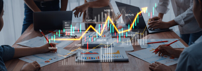 A vibrant business meeting scene featuring professionals analyzing data and charts on a wooden table, emphasizing collaboration and financial strategy development. Scalp