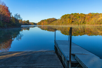 mirror lake with boat dock in autumn