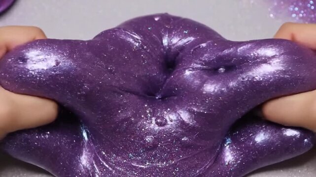 Close-up of a hand poking sparkling purple slime with glitter, ASMR sensory play