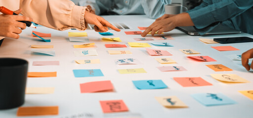 A vibrant scene of diverse hands reaching for colorful sticky notes on a white table, highlighting creative collaboration and brainstorming in a modern workspace setting. SACTR