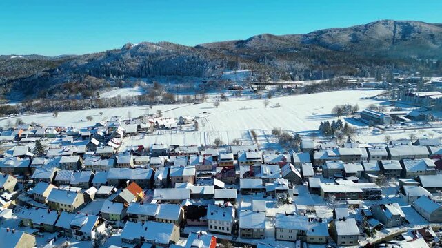 Aerial view of snow-covered Delnice, Croatia, nestled in a valley with a distant cloud inversion. Winter landscape under a clear blue sky. Perfect for winter travel.