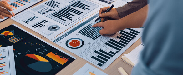 A group of professionals collaborates over various business charts and graphs, engaging in lively discussion and strategic planning for future projects and performance evaluation. SACTR