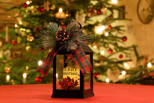 Weihnachtslaterne mit weihnachtlichen Accessoires vor Christbaum