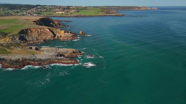 Aerial drone flying over ocean with coastal cliff landscape on left side Spain