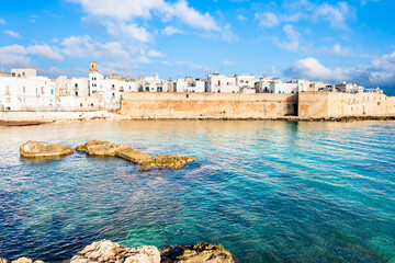 Coastal fortress and old town walls reflected in the turquoise waters of the Adriatic Sea in Monopoli town, Apulia, Italy