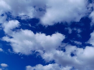 Beautiful blue sky with fluffy white cumulus clouds on a bright sunny day.