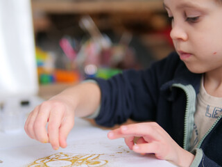 Young Boy Sprinkling Gold Glitter onto a Drawing for a Creative Craft Project - Child Focused on DIY Holiday Art with Glitter and Sketches