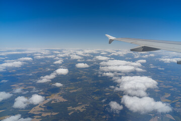 Fototapeta premium An airplane wing extends into a clear blue sky above a thick layer of white clouds. The scene captures the feeling of flying high on a sunny day.