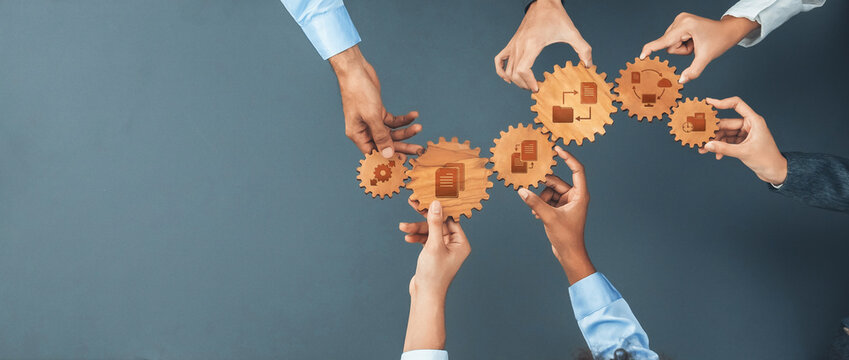 A diverse group of hands working together to hold interlocking gears, symbolizing collaboration and strategic planning in management for business success. Amity