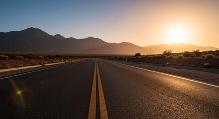 Fototapeta premium Asphalt road stretches into distance toward sunset between mountains and desert