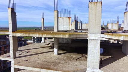 Beneath a vibrant blue sky, a concrete structure emerges, revealing its unfinished floors and rugged framework. Sunlight casts shadows, highlighting the progress in urban construction.