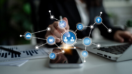 A businesswoman interacts with a smartphone displaying digital network icons, symbolizing technology, data analysis, and innovation in a modern office setting. Tessel