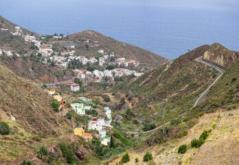 Colorful hillside village of Taganana with white and pastel houses clustered along winding TF-134 road above deep blue ocean, Tenerife, Canary Islands, Spain.