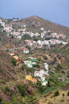 Colorful hillside village of Taganana with white and pastel houses clustered along winding TF-134 road above deep blue ocean, Tenerife, Canary Islands, Spain.