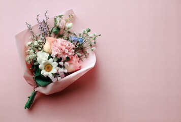 Delicate floral bouquet with roses and wildflowers wrapped in pink paper isolated on pastel backgrou