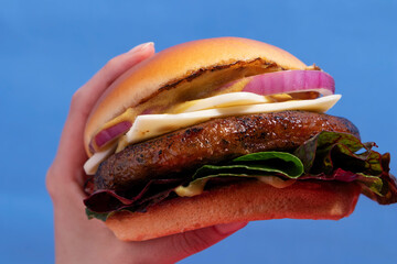 Hand Grasping a Mouth-Watering Cheeseburger